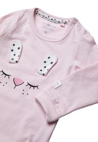 Rosa Baby-Overall mit schwarz-weißen gepunkteten Hasenohren und geschlossenen Augen auf der Vorderseite, ausgestattet mit Druckknöpfen an der Schulter.
