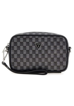 Petit sac bracelet rectangulaire Guess avec motif à carreaux noirs et gris, logo triangulaire de la marque et bandoulière amovible sur fond blanc.