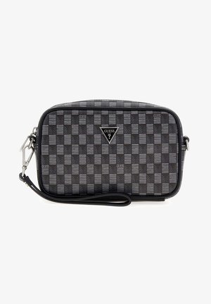 Petit sac bracelet rectangulaire Guess avec motif à carreaux noirs et gris, logo triangulaire de la marque et bandoulière amovible sur fond blanc.