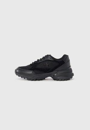 Sneaker sportive nere in materiali mesh e suede, con punta arrotondata, suole testurizzate e un logo discreto sul lato.