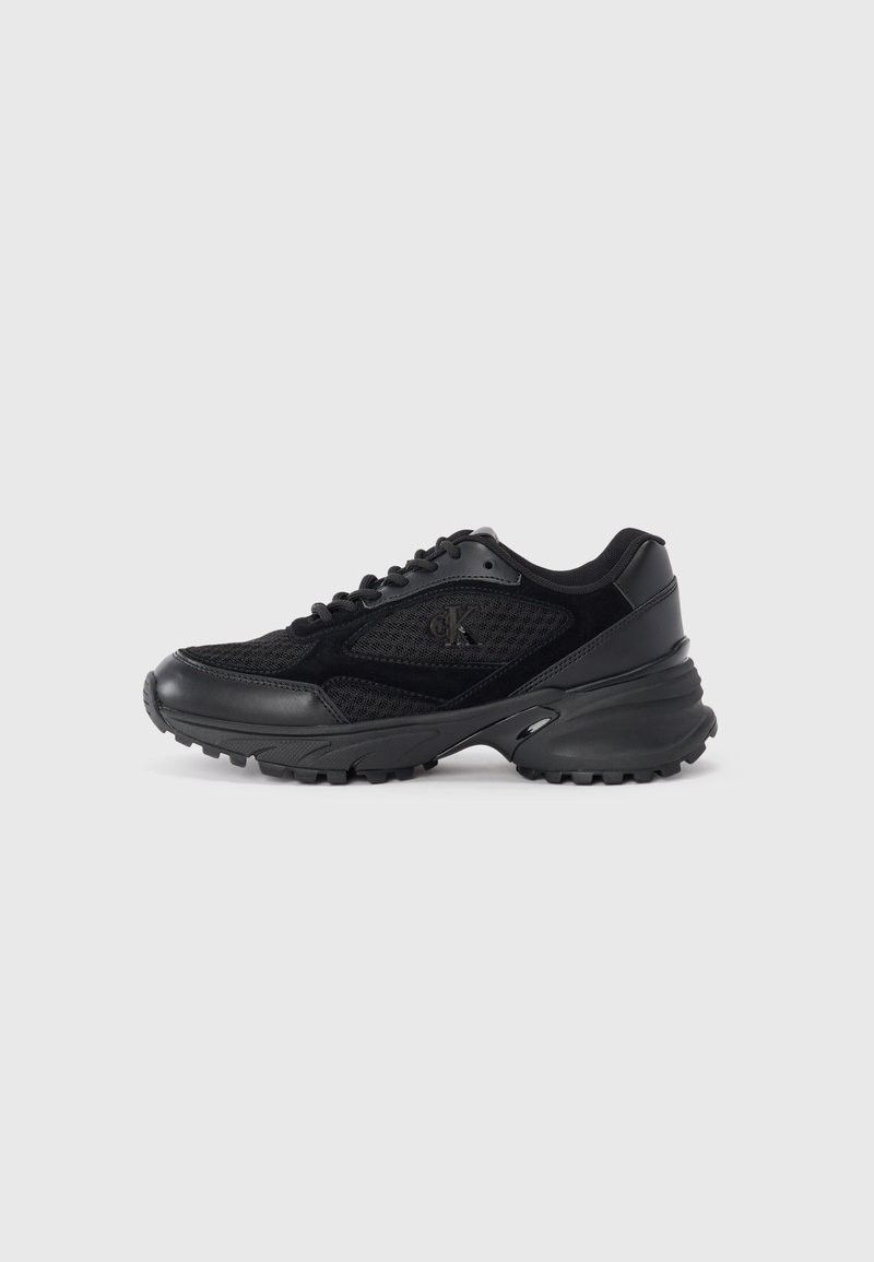 Sneaker sportive nere in materiali mesh e suede, con punta arrotondata, suole testurizzate e un logo discreto sul lato.