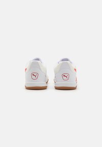 Chaussures de sport blanches avec des accents rouges et des semelles en caoutchouc naturel. Présente un logo sur le talon et un col rembourré pour le confort. Design bas.