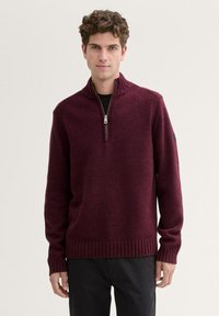 Burgunderfarbener Strickpullover mit Reißverschlusskragen, gerippten Bündchen und Saum. Hat strukturierte Schulterakzente und ein lockeres Fit-Design.