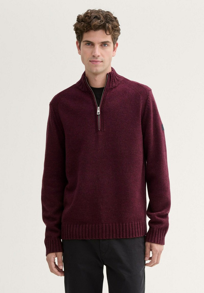 Burgunderfarbener Strickpullover mit Reißverschlusskragen, gerippten Bündchen und Saum. Hat strukturierte Schulterakzente und ein lockeres Fit-Design.