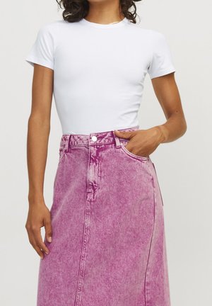 Hvid kortærmet t-shirt kombineret med en højtaljet pink denim nederdel, der har knaplukning og en let falmet tekstur.