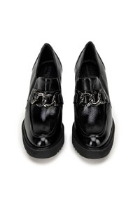 Černé lakované boty se špičatou špičkou, s kovovým řetízkem napříč nártem a robustní černou podrážkou.