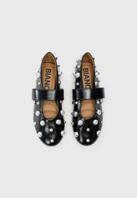 Μαύρα δερμάτινα παπούτσια με στρογγυλή μύτη, διακοσμημένα με ασημένιες ακίδες και μια φαρδιά ζώνη στο μπροστινό μέρος. Καφέ πάτος με ορατό το όνομα της μάρκας.