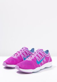 Fialové síťované sportovní boty s modrým logem Nike. Mají nízkoprofilový design, texturovanou látku a polstrovanou podrážku. Šňůrky jsou součástí.