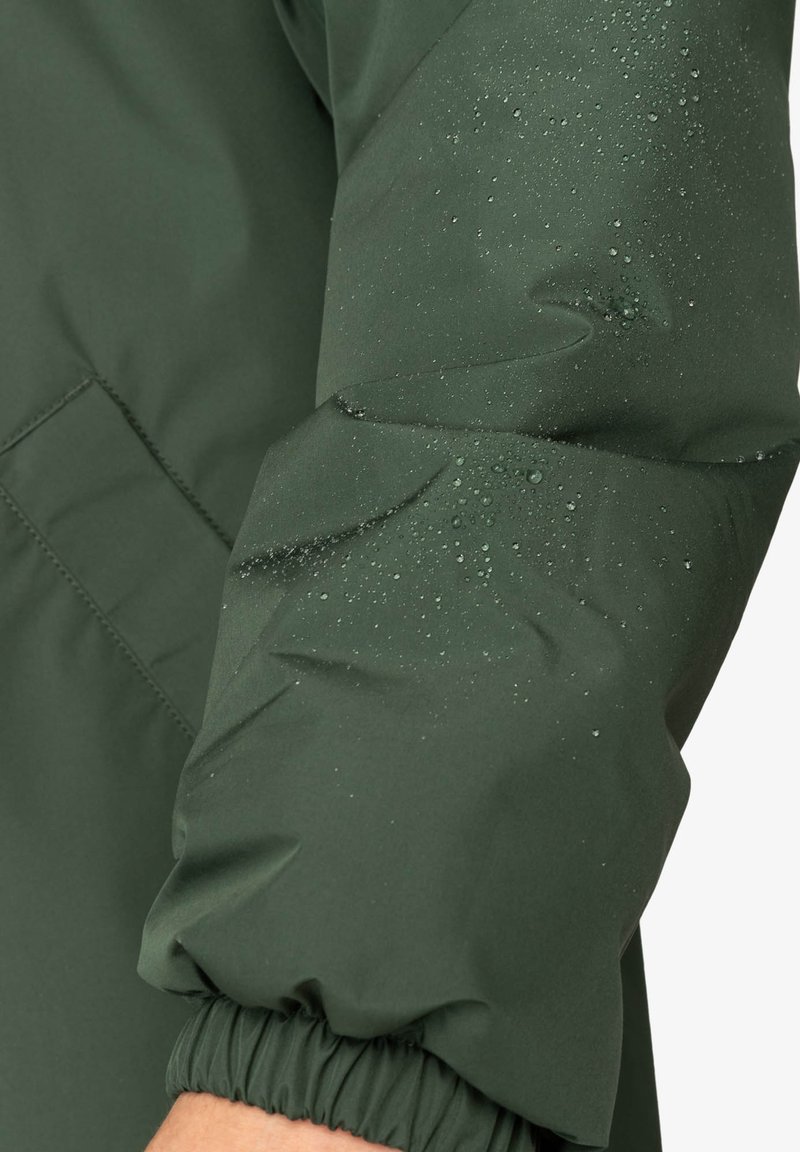 Manica di giacca imbottita verde con gocce d'acqua su un tessuto liscio e testurizzato. Presenta un polsino elastico e un sottile dettaglio di cucitura.