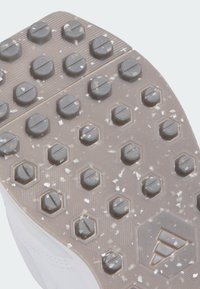 Hvid atletiksko-sål med tekstureret, gummibelagt overflade. Har runde og sekskantede grebsknopper, for det meste grå, med en støvet effekt.