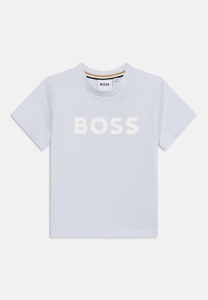 Maglietta per bambino a maniche corte di colore azzurro chiaro con il logo BOSS bianco sul petto e due bottoni automatici sulla spalla sinistra.