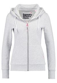 Sudadera con cremallera de color gris claro, con textura de forro polar, cordones, un bolsillo tipo canguro y una etiqueta de logotipo impresa dentro del cuello.