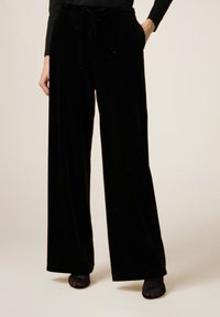Zwarte fluwelen wijde pantalons met een trekkoord in de taille en subtiele versieringen, ontworpen voor comfort en een ontspannen pasvorm.
