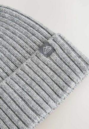 Grå strikket beanie med ribbet tekstur. Har et gråt stofmærke med et logo. Materialet ser blødt og strækbart ud.