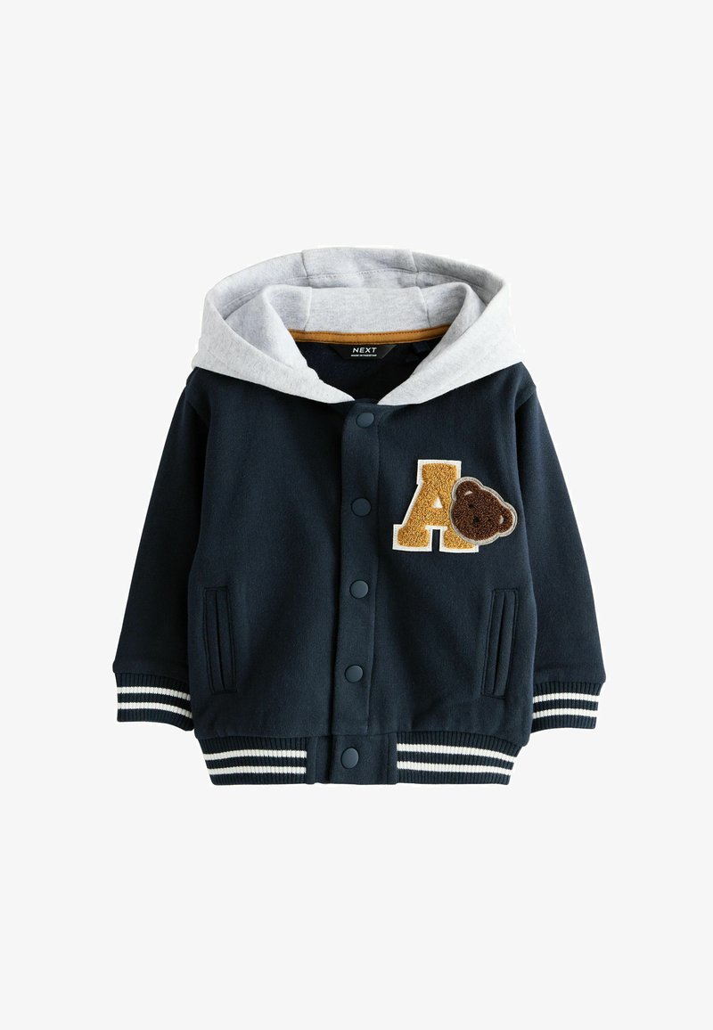 Tumed sinine kapuutsiga jakk halli voodriga, aplikaat "A" ja karupatchiga, triibulised soonikkoes varrukad, nupuvääratus ja küljetaskud.