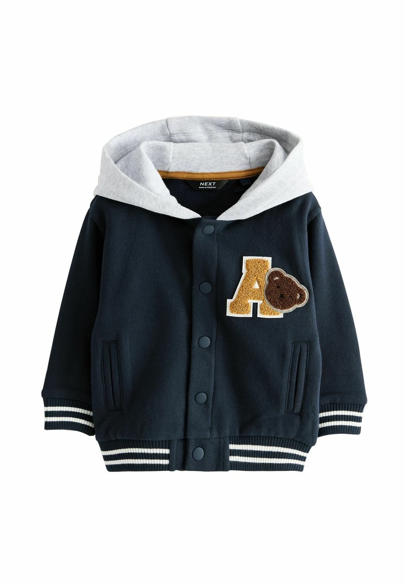 Veste à capuche bleu marine avec doublure grise, appliqué "A" et patch d'ours, poignets en tricot rayé, fermeture à boutons et poches latérales.