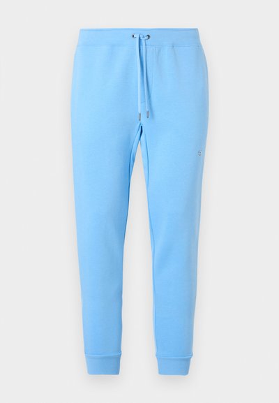 Pantalon de jogging bleu clair avec taille élastique, cordon de serrage ajustable, chevilles resserrées et logo discret sur la cuisse droite.