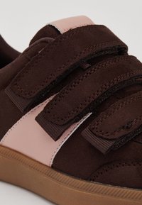 Braunes und pinkes Schuhwerk mit zwei Klettverschlüssen, aus Wildleder und synthetischen Materialien, einer Gummisohle und einer glatten Textur mit genähten Details.