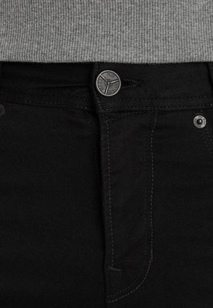 Jeans in denim neri con una finitura texturizzata, dotati di un bottone metallico, cuciture a contrasto e tasche standard.