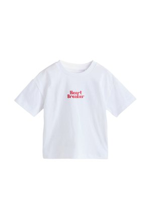 Biała koszulka z krótkim rękawem z czerwonym napisem „Heart Breaker” umieszczonym na środku klatki piersiowej, prezentowana na jednolitym białym tle.