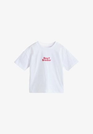 Biała koszulka z krótkim rękawem z czerwonym napisem „Heart Breaker” umieszczonym na środku klatki piersiowej, prezentowana na jednolitym białym tle.