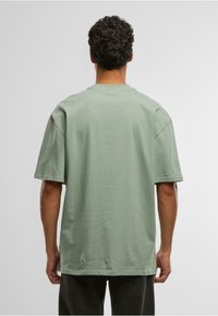 Green cotton t-shirt with a relaxed fit, short sleeves, and a crew neck; features a smooth texture and is unadorned with patterns or accents.