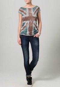 Grå T-shirt med en bleknad Union Jack-design; korta ärmar, lätt slitage och utsmyckningar på axlarna; matchas med mörka jeans.