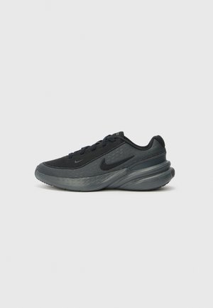 Črne atletske čevlje z mrežastim zgornjim delom, teksturiranim dizajnom in oblazinjenim podplatom. Imajo Nike logo in zaobljen petni del. Minimalistična in poenostavljena oblika.