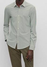 Overhemd met knopen in lichtgroen met een klein geruit patroon, lange mouwen en een puntkraag. Gemaakt van gladde stof, met een slim-fit pasvorm.