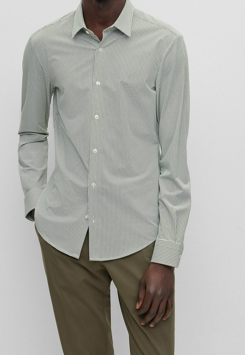 Overhemd met knopen in lichtgroen met een klein geruit patroon, lange mouwen en een puntkraag. Gemaakt van gladde stof, met een slim-fit pasvorm.