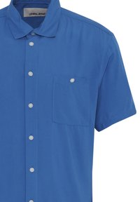 Camisa de manga corta en tejido azul brillante, con un delantero abotonado, un bolsillo de parche en el lado izquierdo del pecho y botones blancos.