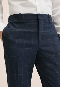 Námořnicky modré kostkované kalhoty z texturované látky, s hladkým předním dílem, poutky na pásek a úzkým střihem s jemnými bílými mřížkovými liniemi.