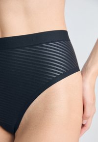 Svart høyt liv undertøy med en jevn linning og teksturert stripete design, laget av elastisk og lett materiale.