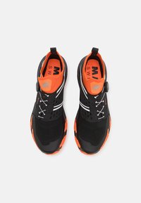 Czarne buty sportowe z pomarańczowymi akcentami, siatkową teksturą, okrągłym noskiem, elastycznymi sznurówkami i okrąłym pokrętłem do regulacji dopasowania. Białe paski po bokach.
