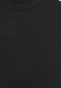 Musta poolikauluspaita, joka on valmistettu sileästä ja joustavasta kankaasta, lähellä kehoa istuvalla muotoilulla ja korkealla kaula-aukolla, tarjoten siistin ja saumoittoman ilmeen.