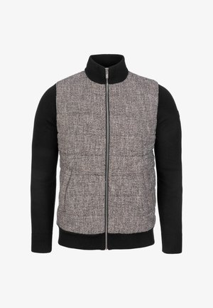 Chaleco acolchado con delantero gris texturizado y mangas negras de punto. Cuenta con cuello alto y cierre frontal con cremallera. Dos bolsillos laterales.