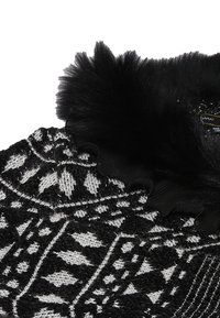 Tessuto a maglia con motivo in bianco e nero, con una finitura texture, caratterizzato da un morbido colletto in pelliccia sintetica nera e dettagli con bordo scallop.