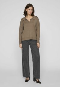 Suéter marrón de punto con cuello, combinado con jeans de pierna ancha de talle alto en gris oscuro y zapatos negros de tacón cuadrado pulidos.