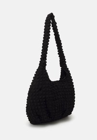 Borsa a spalla nera in tessuto con una superficie strutturata e irregolare, dotata di una tracolla ampia e di una forma bombata. Senza hardware o accenti visibili.