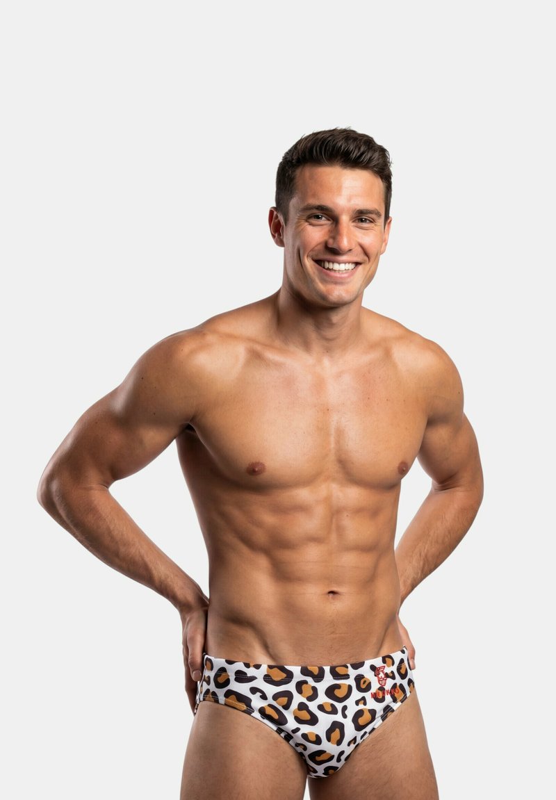 Bañador tipo slip con estampado de leopardo blanco con manchas negras y marrones, con un detalle en rojo. Tejido suave, diseño ajustado y corte de tiro bajo.