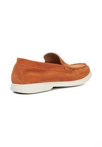 Suede slip-on loafers in burnt orange with a rounded toe, contrasting white rubber sole, and minimal stitching detail along the edges.