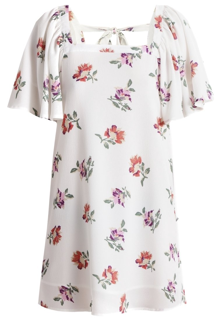 Vestido blanco floral con mangas cortas y onduladas, que presenta patrones de flores rojas, moradas y verdes por toda su superficie. Escote cuadrado con detalle de lazo en la parte posterior.