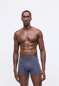 Szürke boxer alsónadrág, testhez álló kialakítással, sima anyagból készült. Fekete derékpántja a "BJÖRN BORG" márkázással rendelkezik.