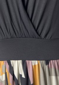 Lühikeste varrukate ja tumeda halli pealmise osaga kleit, millel on kokku tõmmatud vöökoht ja mustriga seelik muted värvides: kollane, roosa ja must.