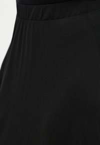 Μαύρη φούστα από απαλό, ελαφρύ ύφασμα, με ελαστική μέση και πιετέ σχέδιο για μια αέρινη σιλουέτα.