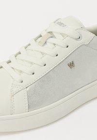 Sneaker bianco con pelle liscia e accenti in suede testurizzato, lacci bianchi e dettagli metallici sottili. Design minimalista complessivo.