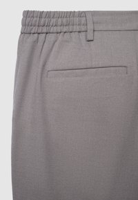 Graue gewebte Hose mit elastischem Bund, einer Gesäßtasche und Fischgrätmuster.