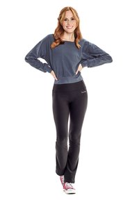 Grauer langärmeliger Sweatshirt mit einem verkürzten Design, kombiniert mit schwarzen enganliegenden Leggings. Das Model trägt rote und weiße Sneakers.
