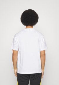 Biała bawełniana koszulka z krótkim rękawem i okrągłym dekoltem, z gładkim tyłem i luźnym krojem.