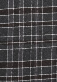 Črn in sivo karirast material z teksturirano površino. Vsebuje bele mrežne črte, ki ustvarjajo vzorec kvadratov in pravokotnikov.